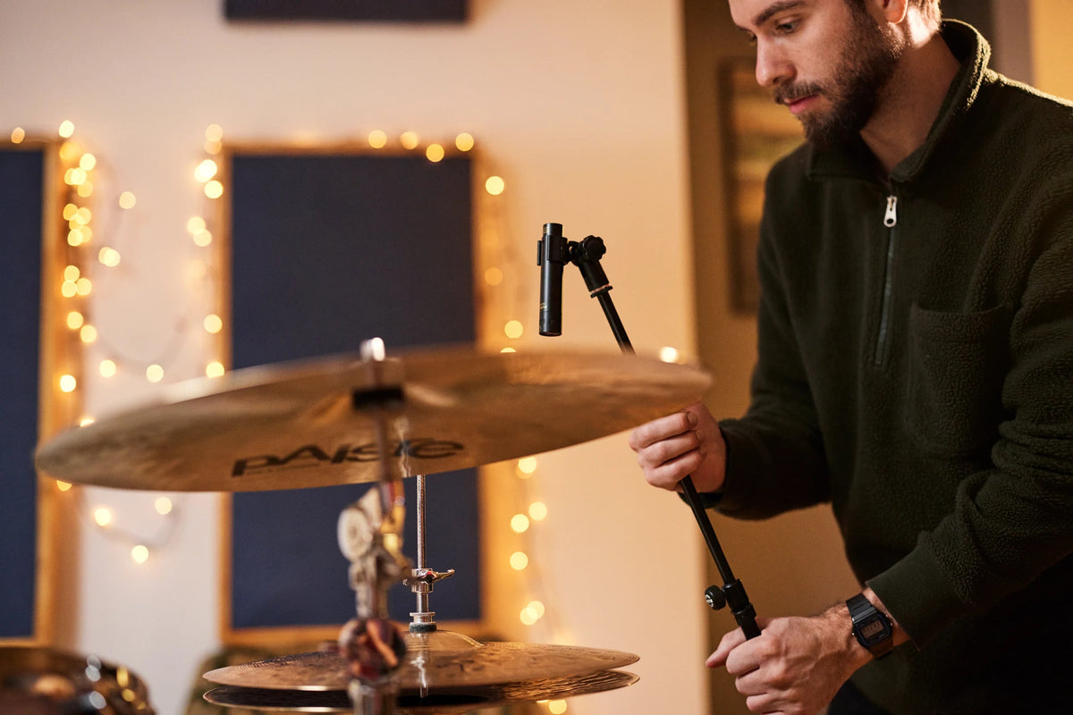 Músico ajusta un micrófono Audix sobre su pedestal en un estudio de grabación